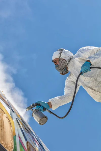 Aircraft painting and sandblasting. Spray painting, airplane wing. Worker in coverall using airbrush.