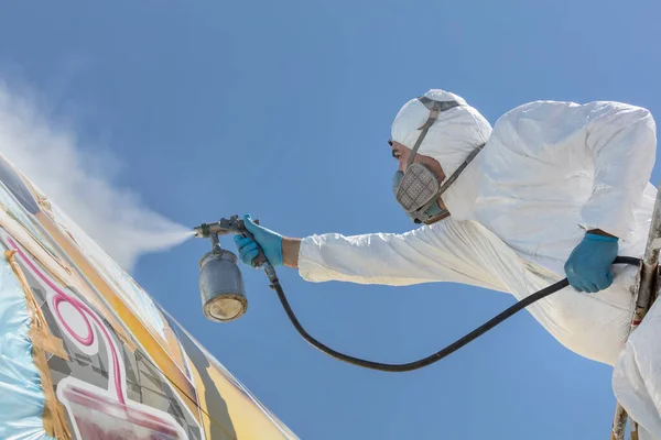 Aircraft painting and sandblasting. Spray painting, airplane wing. Worker in coverall using airbrush.