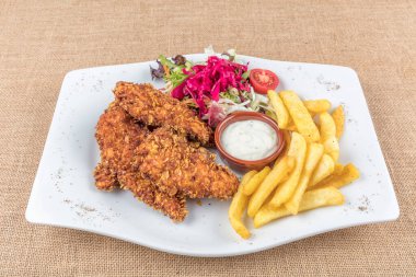 Lezzetli kızarmış tavuk göğsü şeritlerini beyaz tabakta, domates soslu ve limon dilimli eski ahşap masa üzerinde, açık hava pikniği ya da parti için kolay tarif, yukarıdan görüş.