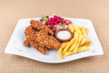 Lezzetli kızarmış tavuk göğsü şeritlerini beyaz tabakta, domates soslu ve limon dilimli eski ahşap masa üzerinde, açık hava pikniği ya da parti için kolay tarif, yukarıdan görüş.