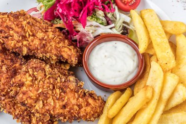 Lezzetli kızarmış tavuk göğsü şeritlerini beyaz tabakta, domates soslu ve limon dilimli eski ahşap masa üzerinde, açık hava pikniği ya da parti için kolay tarif, yukarıdan görüş.