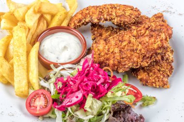 Lezzetli kızarmış tavuk göğsü şeritlerini beyaz tabakta, domates soslu ve limon dilimli eski ahşap masa üzerinde, açık hava pikniği ya da parti için kolay tarif, yukarıdan görüş.