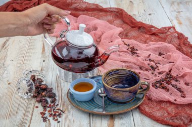 Rosehip çayı: Çay demleme süreci, çay seremonisi, ahşap zemin üzerinde taze demlenmiş gül çayı.