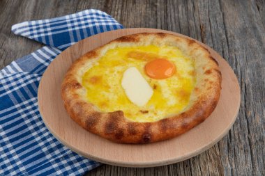 Geleneksel Türk mutfağı; üzerinde karadeniz pita (Karadeniz Pidesi) ekmek, tereyağı ve yumurta bulunan yuvarlak peynir. Kırsal ahşap masa üzerine restoran konsepti.