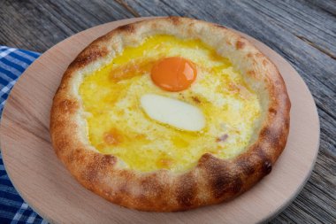 Geleneksel Türk mutfağı; üzerinde karadeniz pita (Karadeniz Pidesi) ekmek, tereyağı ve yumurta bulunan yuvarlak peynir. Kırsal ahşap masa üzerine restoran konsepti.