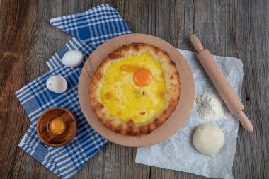 Geleneksel Türk mutfağı; üzerinde karadeniz pita (Karadeniz Pidesi) ekmek, tereyağı ve yumurta bulunan yuvarlak peynir. Kırsal ahşap masa üzerine restoran konsepti.