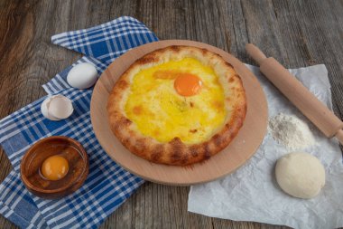 Geleneksel Türk mutfağı; üzerinde karadeniz pita (Karadeniz Pidesi) ekmek, tereyağı ve yumurta bulunan yuvarlak peynir. Kırsal ahşap masa üzerine restoran konsepti.