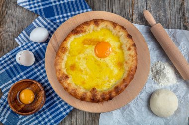Geleneksel Türk mutfağı; üzerinde karadeniz pita (Karadeniz Pidesi) ekmek, tereyağı ve yumurta bulunan yuvarlak peynir. Kırsal ahşap masa üzerine restoran konsepti.