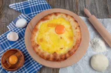 Geleneksel Türk mutfağı; üzerinde karadeniz pita (Karadeniz Pidesi) ekmek, tereyağı ve yumurta bulunan yuvarlak peynir. Kırsal ahşap masa üzerine restoran konsepti.