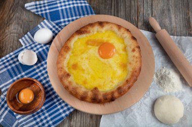 Geleneksel Türk mutfağı; üzerinde karadeniz pita (Karadeniz Pidesi) ekmek, tereyağı ve yumurta bulunan yuvarlak peynir. Kırsal ahşap masa üzerine restoran konsepti.