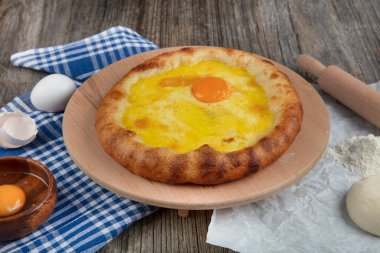 Geleneksel Türk mutfağı; üzerinde karadeniz pita (Karadeniz Pidesi) ekmek, tereyağı ve yumurta bulunan yuvarlak peynir. Kırsal ahşap masa üzerine restoran konsepti.