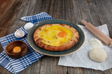 Geleneksel Türk mutfağı; üzerinde karadeniz pita (Karadeniz Pidesi) ekmek, tereyağı ve yumurta bulunan yuvarlak peynir. Kırsal ahşap masa üzerine restoran konsepti.