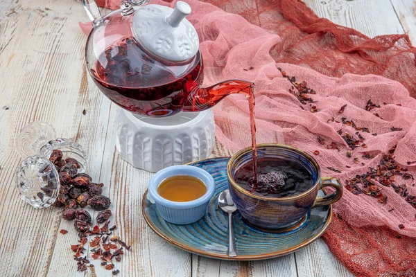 Rosehip tea: Process brewing tea,tea ceremony, Cup of freshly brewed rosehip tea on a wooden background.