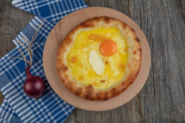 Geleneksel Türk mutfağı; üzerinde karadeniz pita (Karadeniz Pidesi) ekmek, tereyağı ve yumurta bulunan yuvarlak peynir. Kırsal ahşap masa üzerine restoran konsepti.