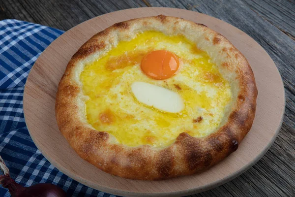 Geleneksel Türk mutfağı; üzerinde karadeniz pita (Karadeniz Pidesi) ekmek, tereyağı ve yumurta bulunan yuvarlak peynir. Kırsal ahşap masa üzerine restoran konsepti.