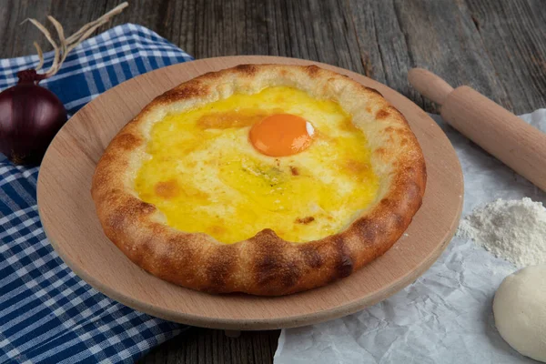 Geleneksel Türk mutfağı; üzerinde karadeniz pita (Karadeniz Pidesi) ekmek, tereyağı ve yumurta bulunan yuvarlak peynir. Kırsal ahşap masa üzerine restoran konsepti.