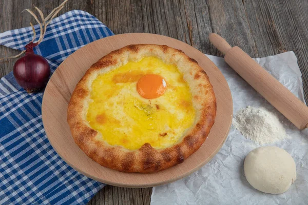 Geleneksel Türk mutfağı; üzerinde karadeniz pita (Karadeniz Pidesi) ekmek, tereyağı ve yumurta bulunan yuvarlak peynir. Kırsal ahşap masa üzerine restoran konsepti.