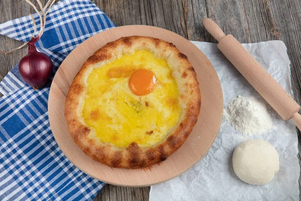 Geleneksel Türk mutfağı; üzerinde karadeniz pita (Karadeniz Pidesi) ekmek, tereyağı ve yumurta bulunan yuvarlak peynir. Kırsal ahşap masa üzerine restoran konsepti.