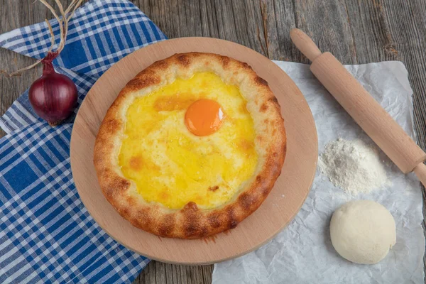 Geleneksel Türk mutfağı; üzerinde karadeniz pita (Karadeniz Pidesi) ekmek, tereyağı ve yumurta bulunan yuvarlak peynir. Kırsal ahşap masa üzerine restoran konsepti.