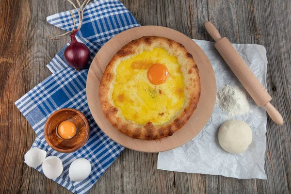 Geleneksel Türk mutfağı; üzerinde karadeniz pita (Karadeniz Pidesi) ekmek, tereyağı ve yumurta bulunan yuvarlak peynir. Kırsal ahşap masa üzerine restoran konsepti.