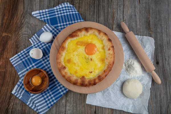 Geleneksel Türk mutfağı; üzerinde karadeniz pita (Karadeniz Pidesi) ekmek, tereyağı ve yumurta bulunan yuvarlak peynir. Kırsal ahşap masa üzerine restoran konsepti.