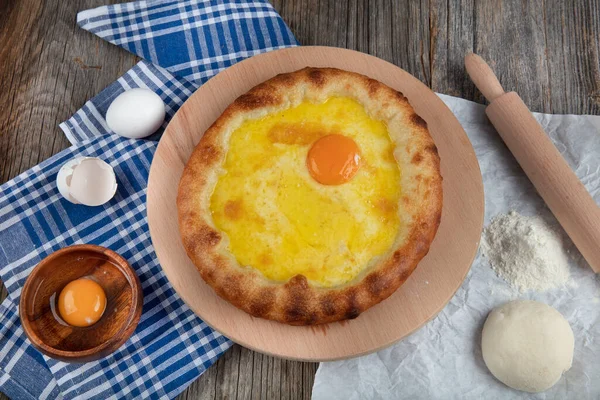 Geleneksel Türk mutfağı; üzerinde karadeniz pita (Karadeniz Pidesi) ekmek, tereyağı ve yumurta bulunan yuvarlak peynir. Kırsal ahşap masa üzerine restoran konsepti.
