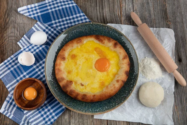 Geleneksel Türk mutfağı; üzerinde karadeniz pita (Karadeniz Pidesi) ekmek, tereyağı ve yumurta bulunan yuvarlak peynir. Kırsal ahşap masa üzerine restoran konsepti.
