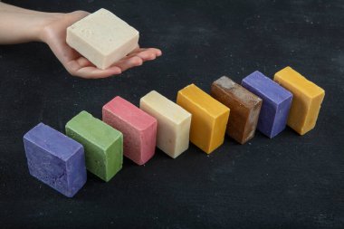 Keçi sütünden doğal spa sabunu. El yapımı, organik sabun, vücut bakımı. Siyah ahşap arka planda birçok farklı el yapımı sabun çubukları