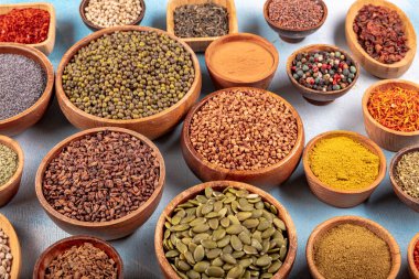 Tabaklardaki ahşap bir masada çeşitli renklerde baharatlar var. Ahşap arka planda çeşitli baharatlar.