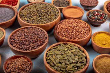 Tabaklardaki ahşap bir masada çeşitli renklerde baharatlar var. Ahşap arka planda çeşitli baharatlar.