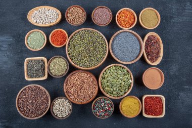 Siyah bir taş masadaki çeşitli renkli baharatların üst görüntüsü. Baharat türlerinin düz görünümü