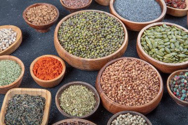 Siyah bir taş masadaki çeşitli renkli baharatların üst görüntüsü. Baharat türlerinin düz görünümü