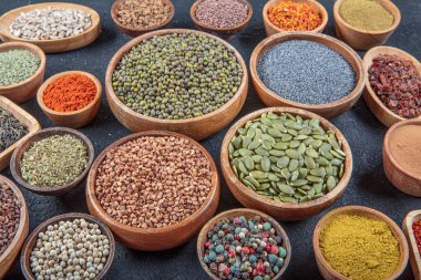 Siyah bir taş masadaki çeşitli renkli baharatların üst görüntüsü. Baharat türlerinin düz görünümü