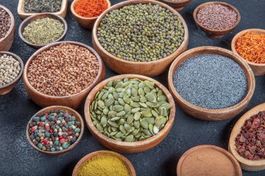 Siyah bir taş masadaki çeşitli renkli baharatların üst görüntüsü. Baharat türlerinin düz görünümü