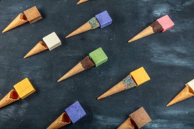 Dondurma külahı ve doğal sabunlar. Siyah ahşap arka planda birçok farklı el yapımı sabun kalıbı var. Yaz mevsimi sağlığı, temizlik konsepti.