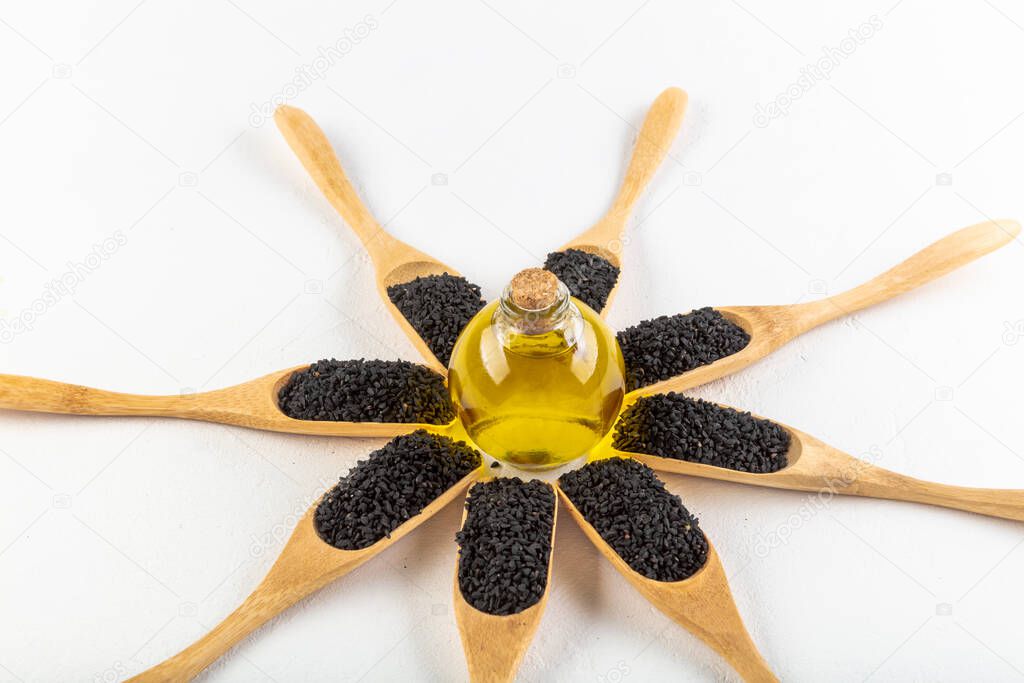 Black cumin oil pill. Black cumin or black caraway spicy seeds in wood spoon isolated on white background. Nigella sativa also known as nigella, kalojeere and kalonji top view
