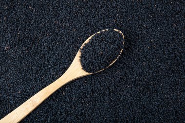 Siyah kimyon. Nigella sativa tohumu dokusu. Kara kimyon temel yağı, Nigella Sativa siyah kimyon yığınında kaşık içinde. Birçok hastalık için organik bitkisel ilaç.