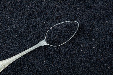 Siyah kimyon. Nigella sativa tohumu dokusu. Kara kimyon temel yağı, Nigella Sativa siyah kimyon yığınında kaşık içinde. Birçok hastalık için organik bitkisel ilaç.