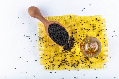 Siyah kimyon tohumları ve kase, tahta kürek ya da kaşık ile gerekli yağ. Nigella Sativa cam şişede. Birçok hastalık için organik bitkisel ilaç.