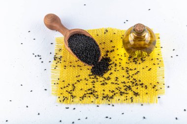 Siyah kimyon tohumları ve kase, tahta kürek ya da kaşık ile gerekli yağ. Nigella Sativa cam şişede. Birçok hastalık için organik bitkisel ilaç.