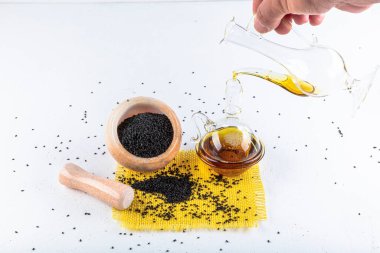 Siyah kimyon tohumları ve kase, tahta kürek ya da kaşık ile gerekli yağ. Nigella Sativa cam şişede. Birçok hastalık için organik bitkisel ilaç.