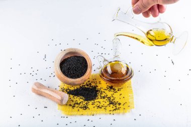 Siyah kimyon tohumları ve kase, tahta kürek ya da kaşık ile gerekli yağ. Nigella Sativa cam şişede. Birçok hastalık için organik bitkisel ilaç.