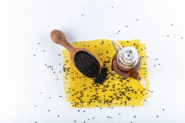 Siyah kimyon tohumları ve kase, tahta kürek ya da kaşık ile gerekli yağ. Nigella Sativa cam şişede. Birçok hastalık için organik bitkisel ilaç.