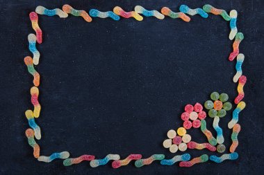 Renkli tatlılar. Lolipop ve şeker. Selamlarınız için en iyi manzara. Farklı lezzetli şekerlerle düz kompozisyon ve siyah ahşap arkaplan üzerine metin için boşluk.