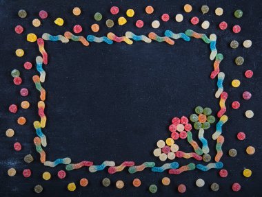 Renkli tatlılar. Lolipop ve şeker. Selamlarınız için en iyi manzara. Farklı lezzetli şekerlerle düz kompozisyon ve siyah ahşap arkaplan üzerine metin için boşluk.