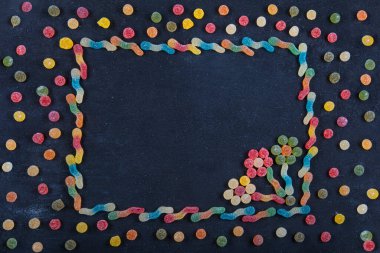 Renkli tatlılar. Lolipop ve şeker. Selamlarınız için en iyi manzara. Farklı lezzetli şekerlerle düz kompozisyon ve siyah ahşap arkaplan üzerine metin için boşluk.