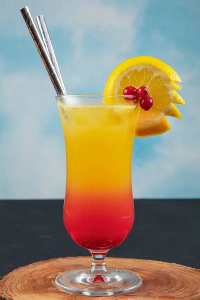 Juicy Orange and Red Tequila Sunrise with a Cherry. Tequila sunrise cocktail on dark wooden table.