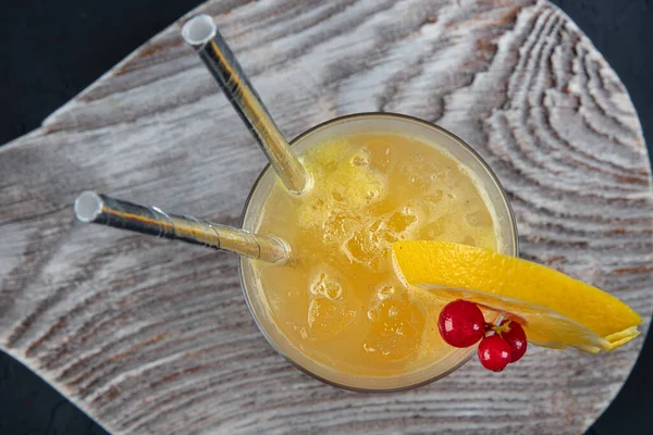 Juicy Orange and Red Tequila Sunrise with a Cherry. Tequila sunrise cocktail on dark wooden table.