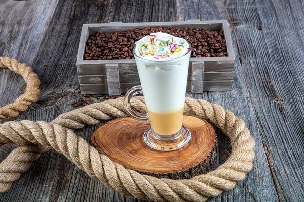 Ein Glas Latte Macchiato Mit Kaffeebohnen Steht Auf Einem Holztisch — Stockfoto