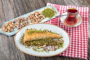 Geleneksel Türk mutfağı. Şam fıstıklı havuç dilimi Türk Baklava ve ahşap masa arkasında çay.